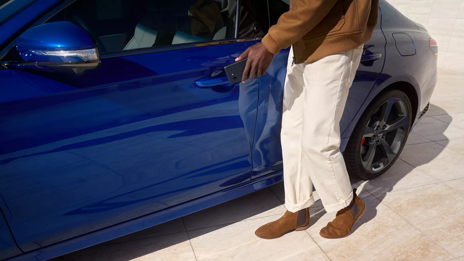Close up of man reaching to open driver side door with digital key on Genesis G70 in Kawah Blue