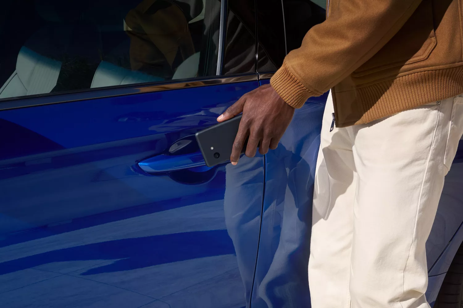 Close up of man reaching to open driver side door with digital key on Genesis G70 in Kawah Blue