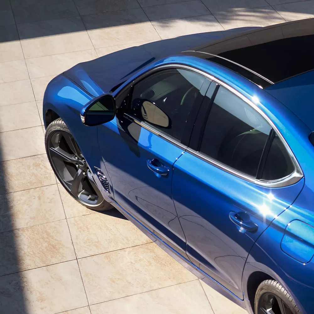 High angle driver side view of Genesis G70 in Kawah Blue