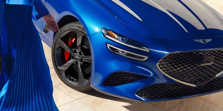 Close up front passenger side view of wheel and grille on Genesis G70 in Kawah Blue