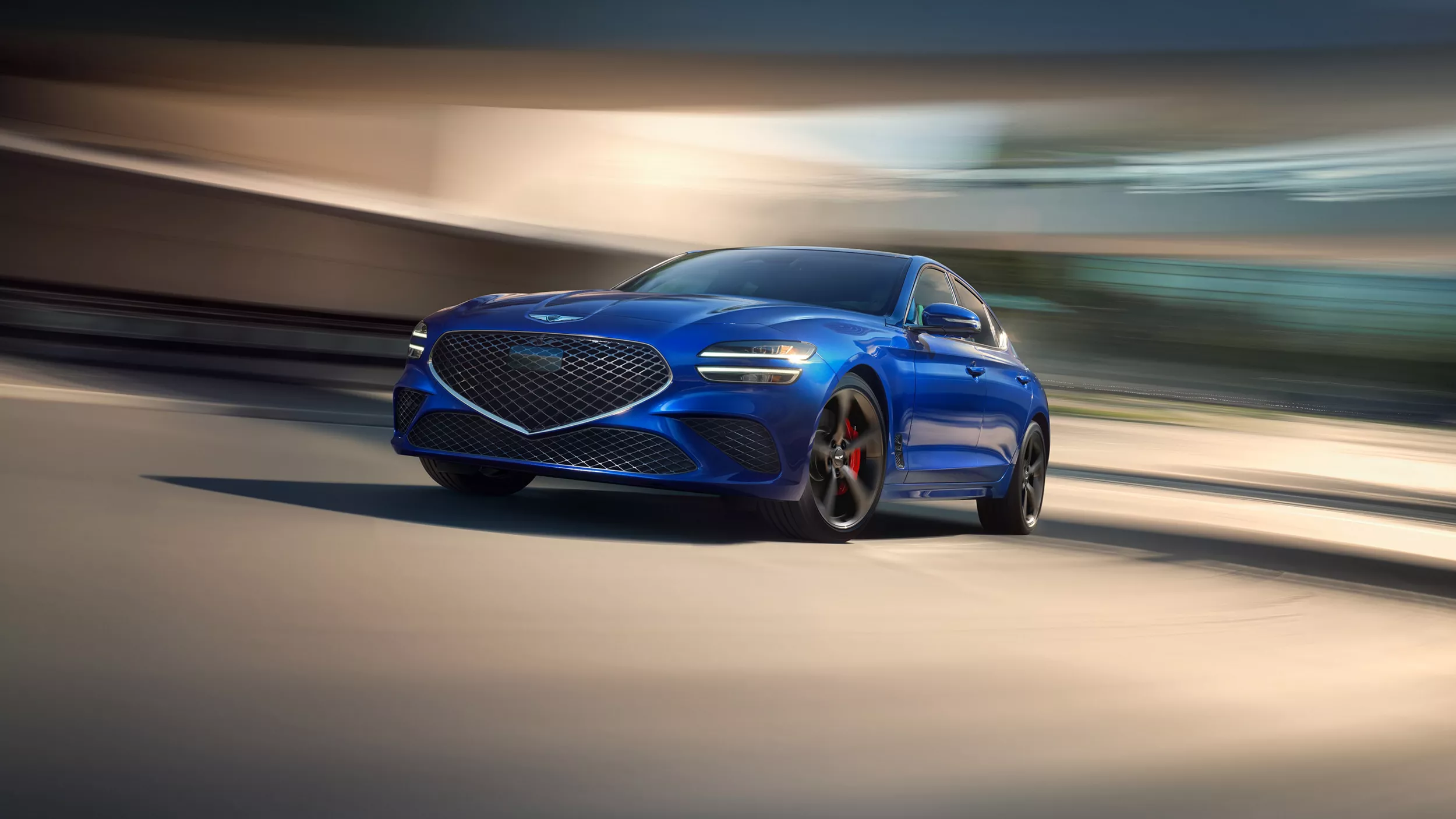 3/4 front driver side angle of 2026 Genesis G70 in Kawah Blue with blurred background