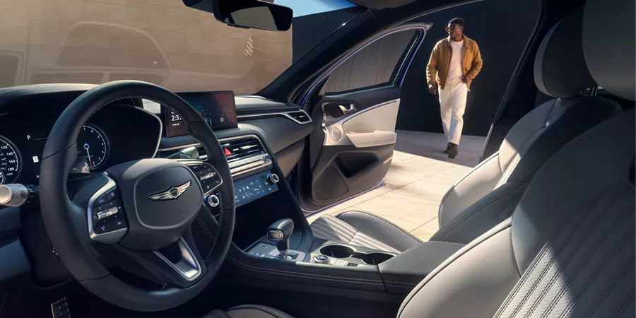 Man walking toward open passenger door, seen from driver seat of Genesis G70 w/ Fog Gray seats