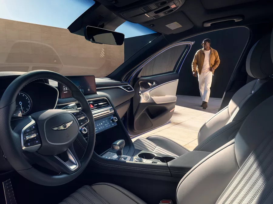 Man walking toward open passenger door, seen from driver seat of Genesis G70 w/ Fog Gray seats