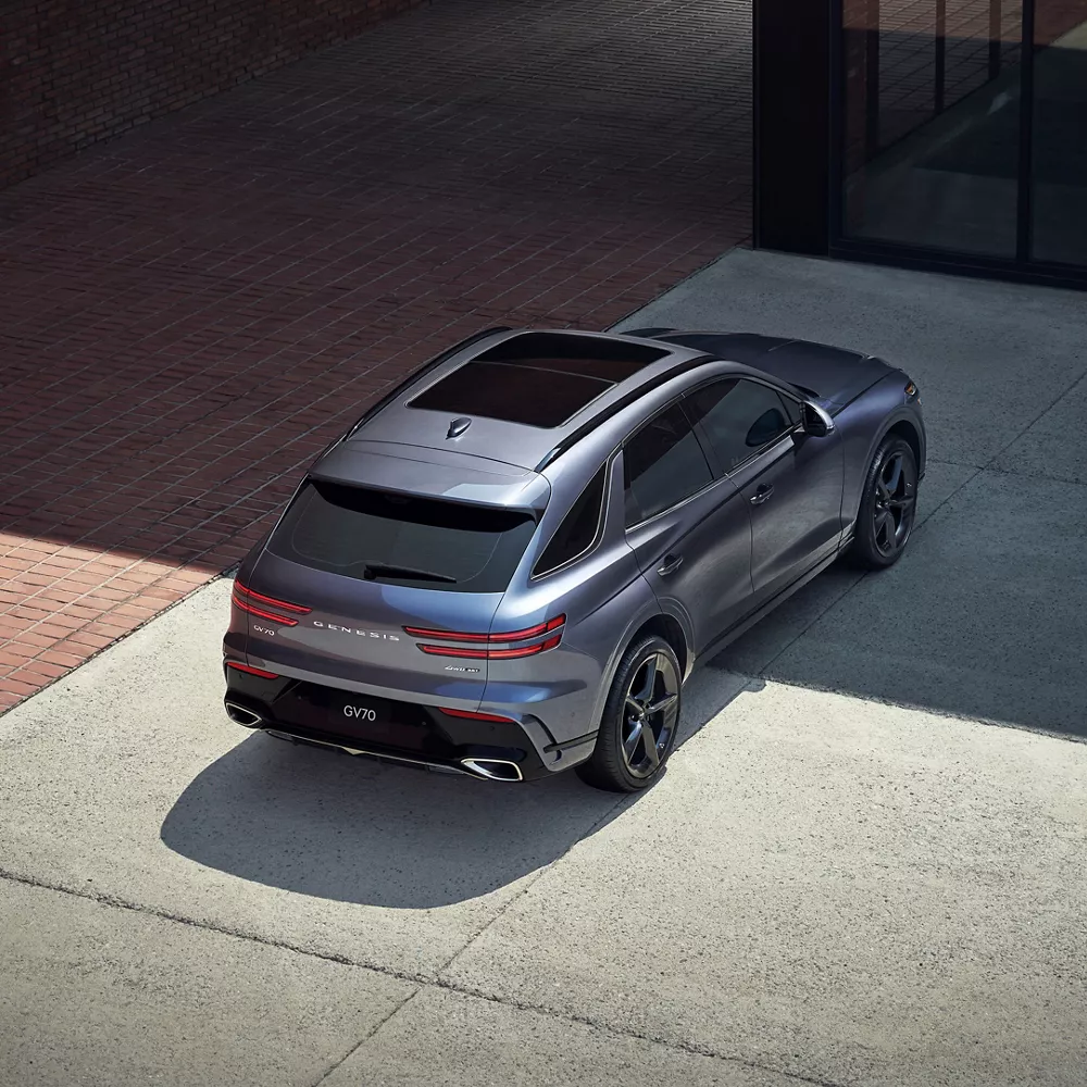 High-angle 3/4 rear passenger view of 2026 Genesis GV70 parked in modern urban environment