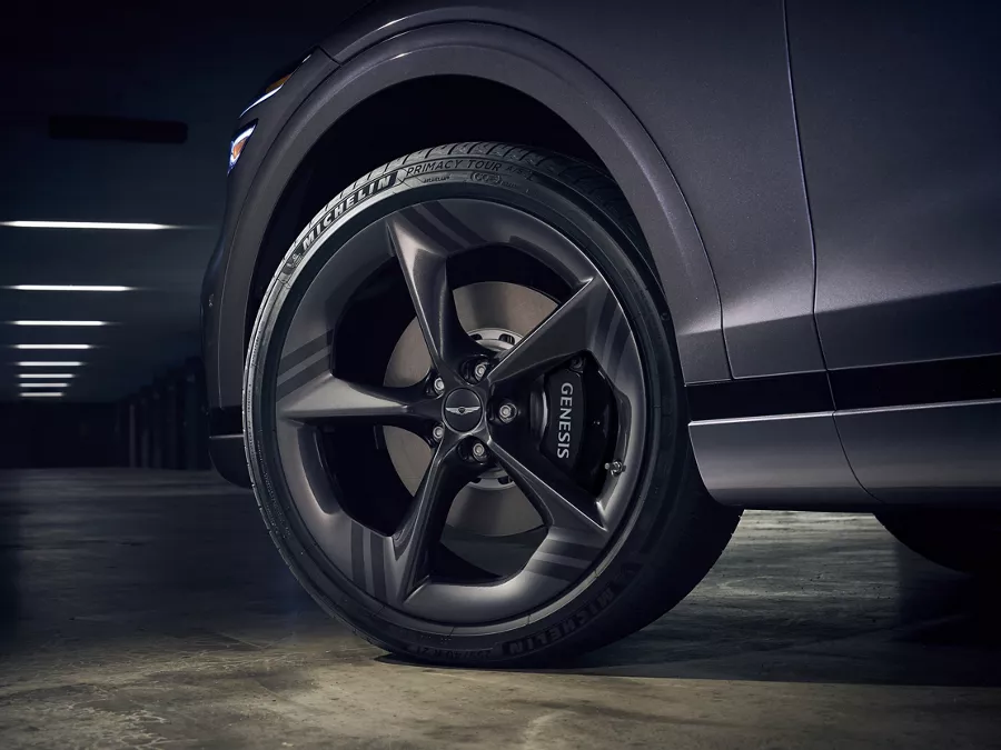 Low-angle close-up of front driver-side wheel and brakes on 2026 Genesis GV70 in Ceres Blue