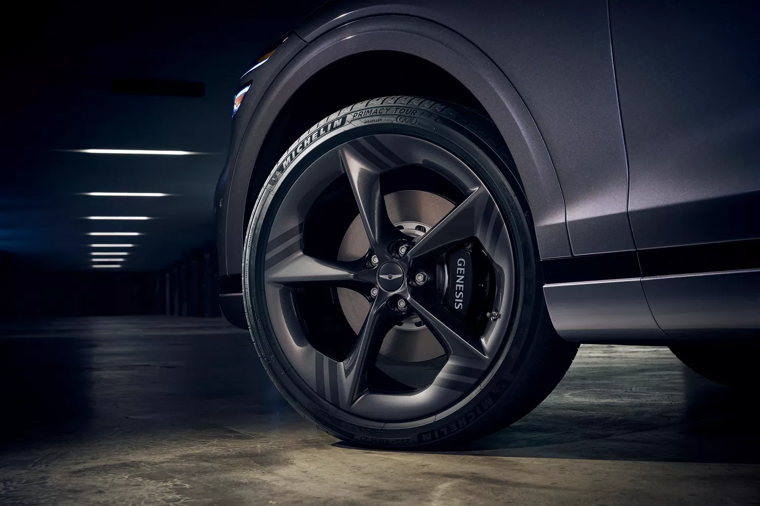 Low angle close-up of Genesis GV70 front driver side wheel, "Genesis" on brake pad