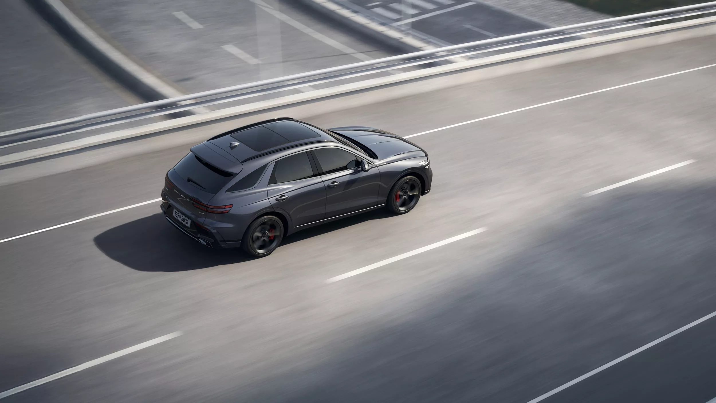 Rear 3/4 aerial view of Genesis GV70 driving across city bridge