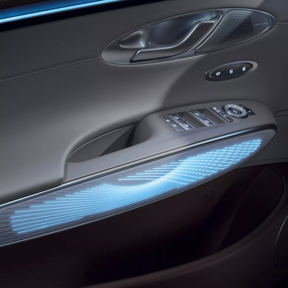 Interior close-up of light blue ambient lighting on driver side door panel inside Genesis GV70