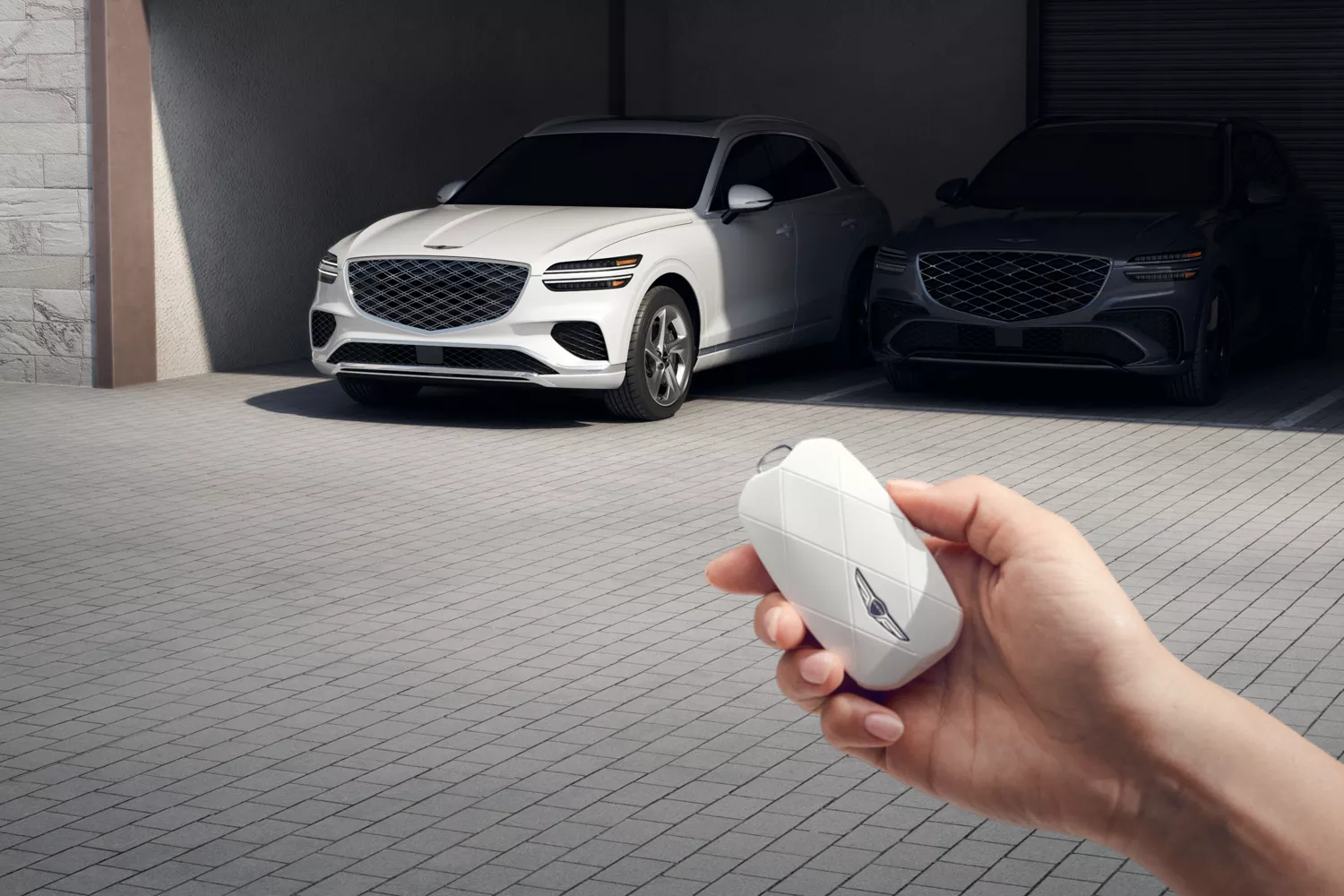 Image of hand holding white Genesis key fob in front of garage with Uyuni White GV70 parked inside