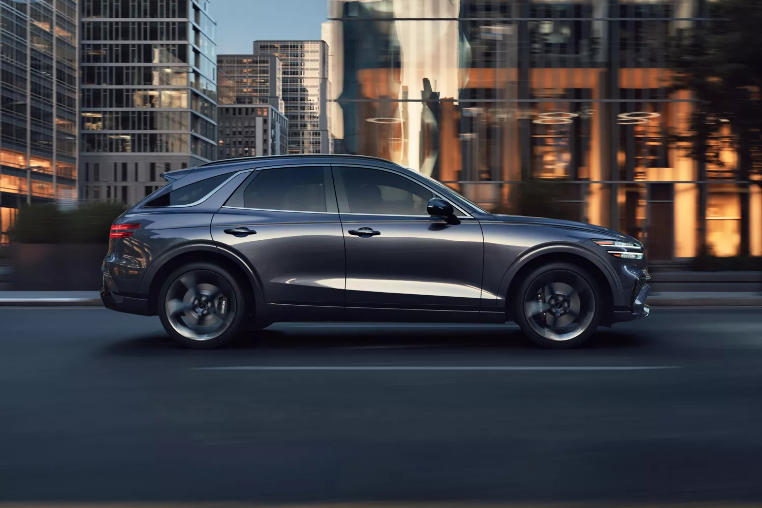 Passenger side profile view of Genesis GV70 driving through city streets
