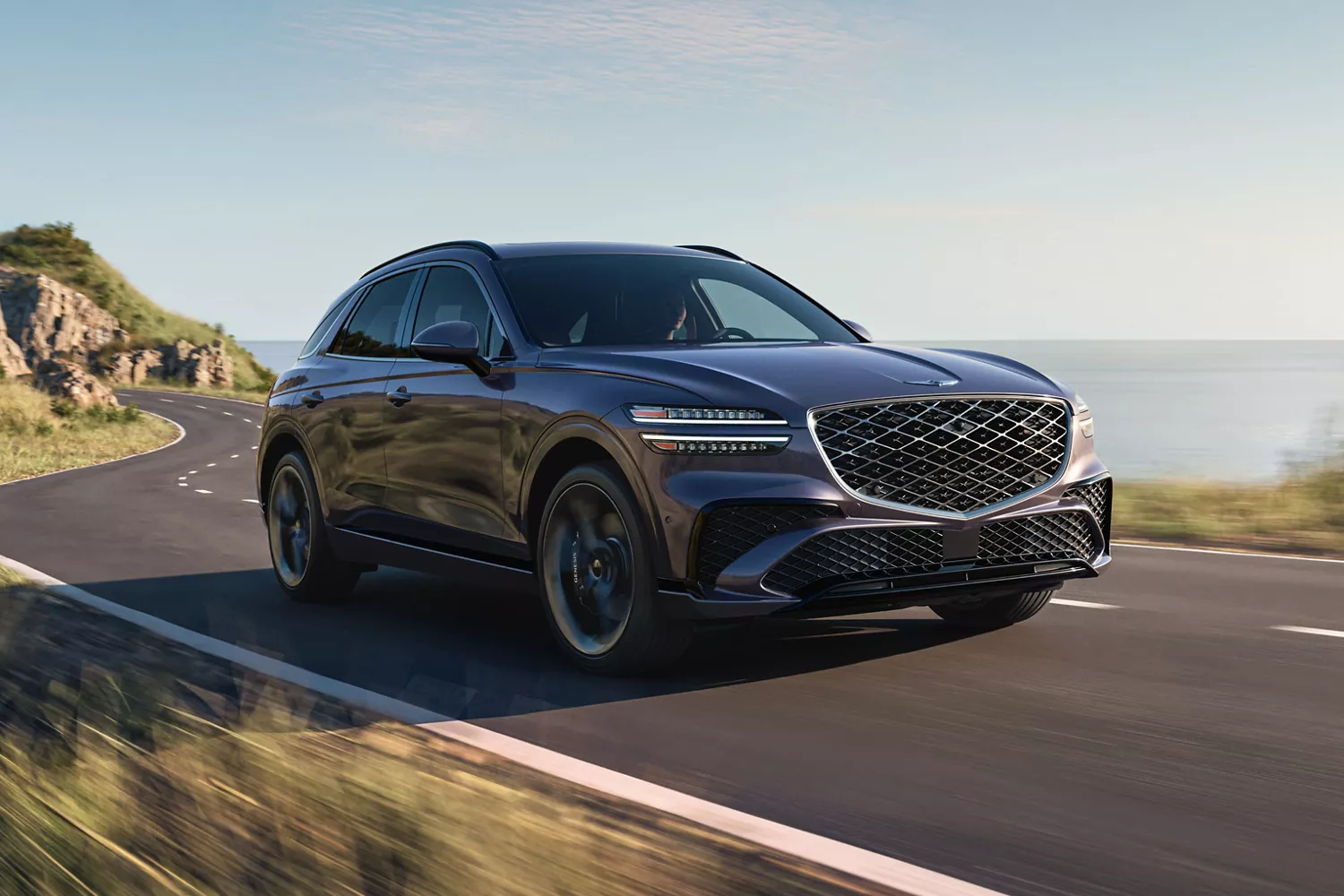 3/4 front passenger side view of Genesis GV70 driving on coastal highway