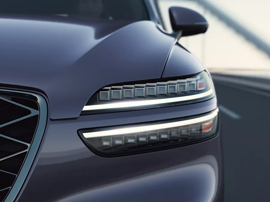 Close-up of grille and driver side headlight on Genesis GV70 in Ceres Blue