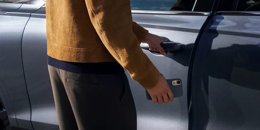 Close up of person opening driver-side door of 2026 Genesis GV70 in ceres blue