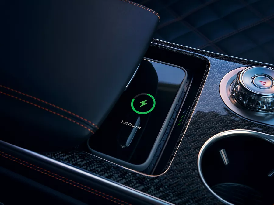 Close-up of 2026 Genesis GV70 center console with wireless charging mat, armrest, and cup holder