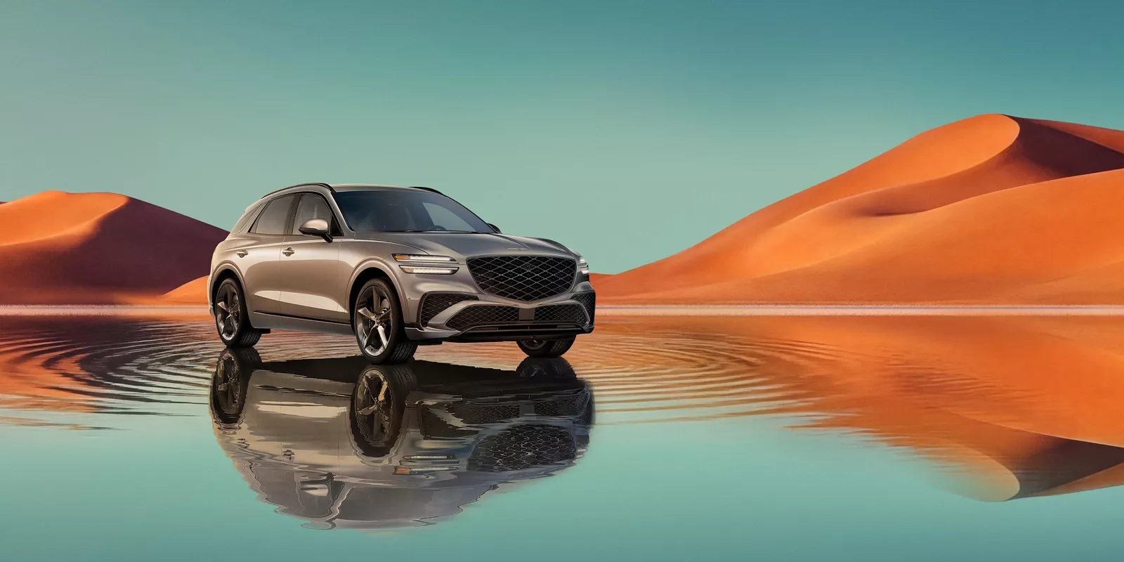 7/8 front passenger view of Savile Silver Genesis GV70 on blue lake w/ orange mountain in background