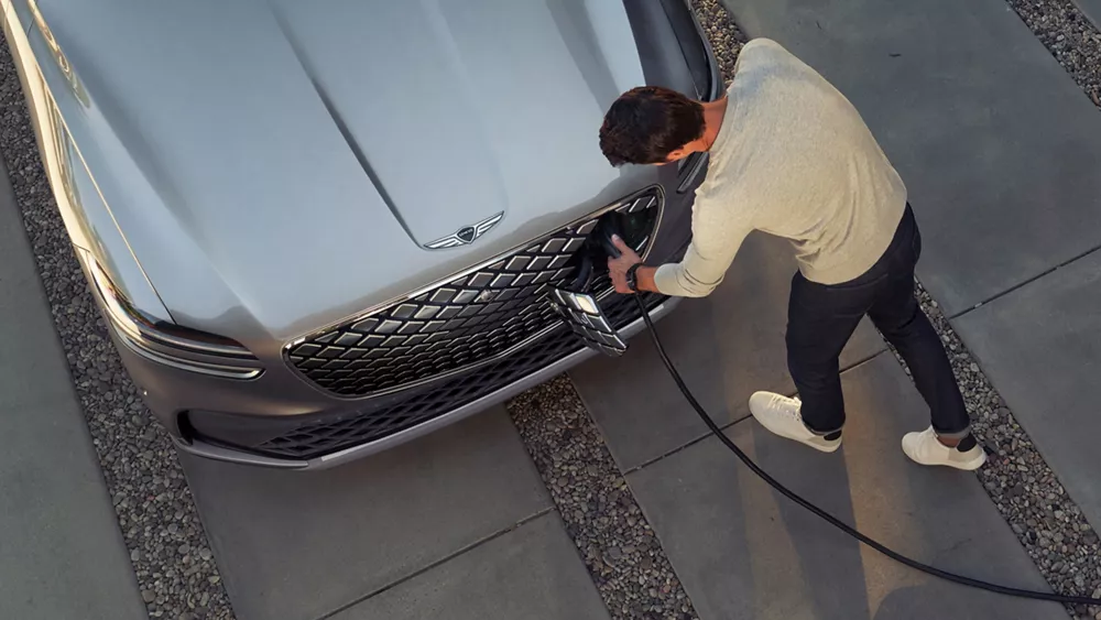 Overhead view of man charging Genesis Electrified GV70 in Savile Silver