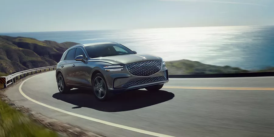3/4 front passenger side view of Genesis Electrified GV70 driving on coastal road
