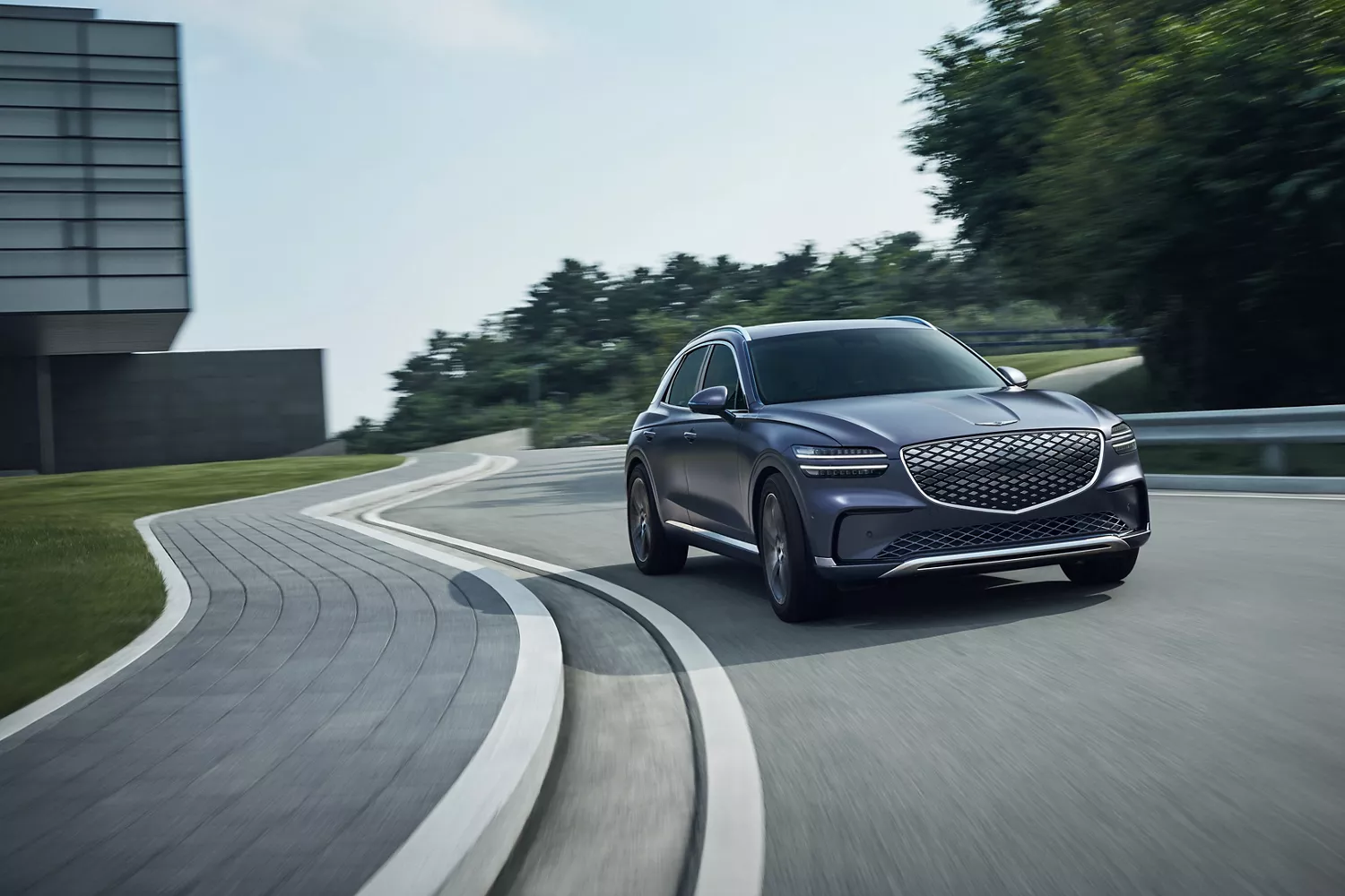 3/4 front passenger side view of Ceres Blue Genesis Electrified GV70 driving on winding road