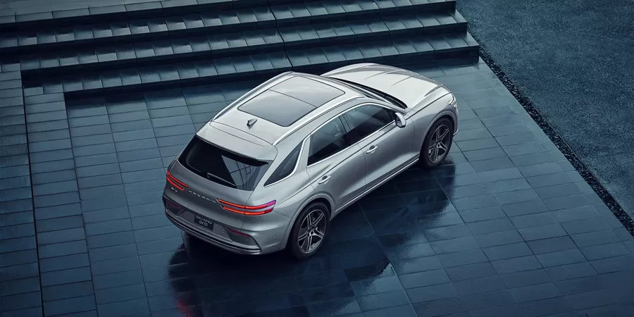 Overhead rear passenger angle of gray Genesis Electrified GV70 parked on dark gray steps