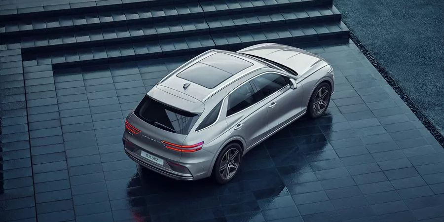 Overhead rear passenger angle of gray Genesis Electrified GV70 parked on dark gray steps