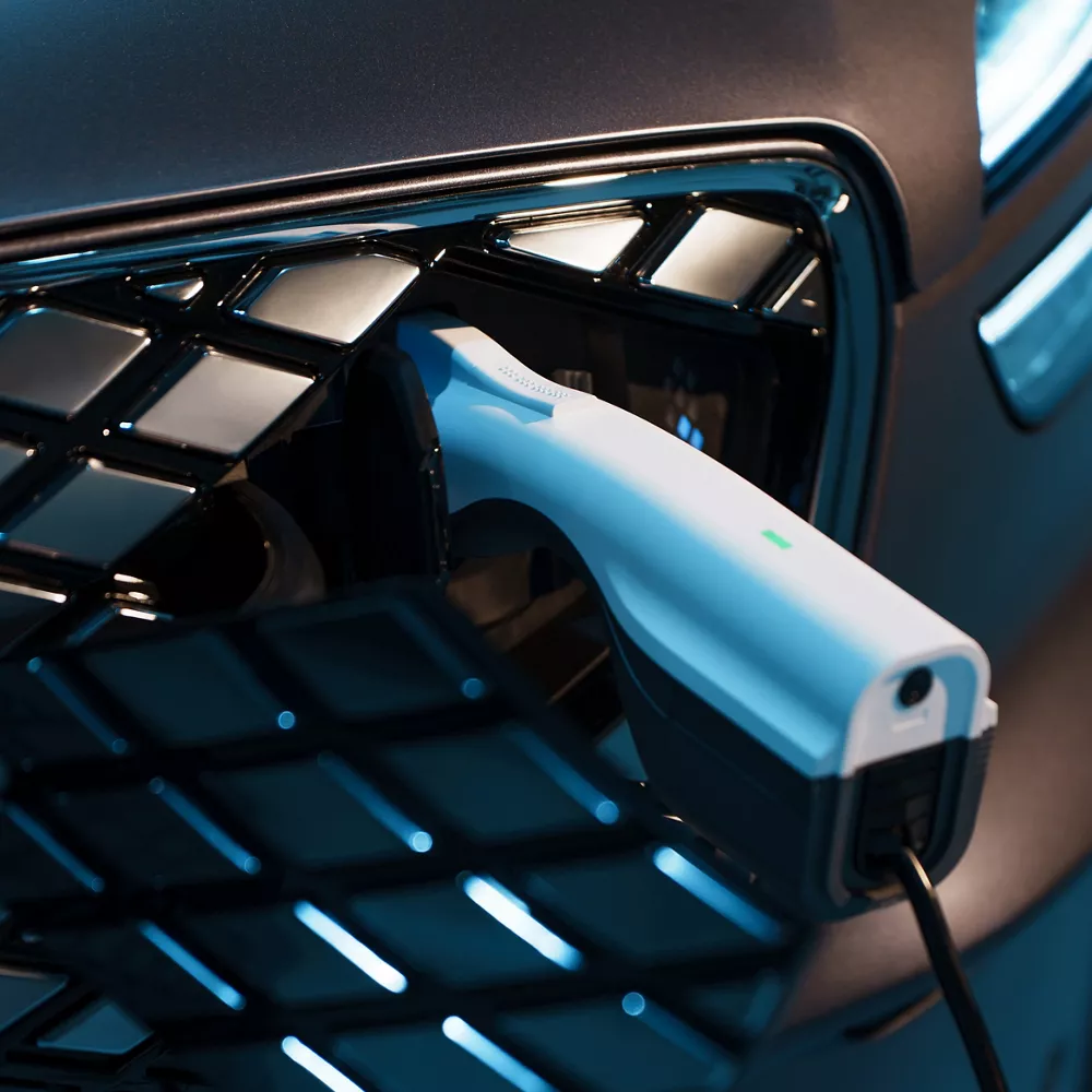 Close up of charger plugged into charge port on the grille of Ceres Blue Genesis Electrified GV70