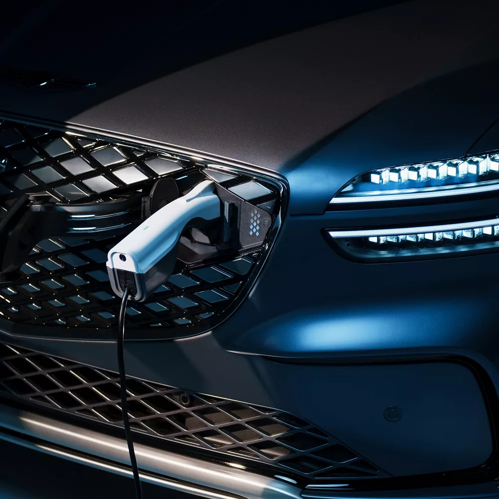Close up of charger plugged into charge port on the grille of Ceres Blue Genesis Electrified GV70