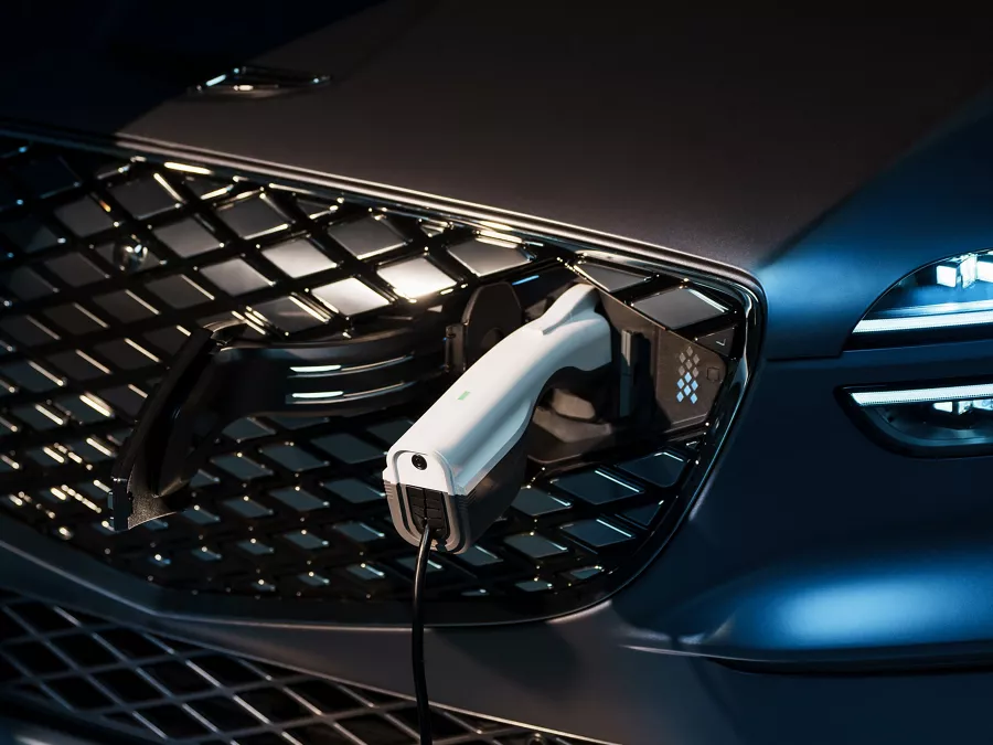 Close-up of front grille charging port with plug inserted on Genesis Electrified GV70