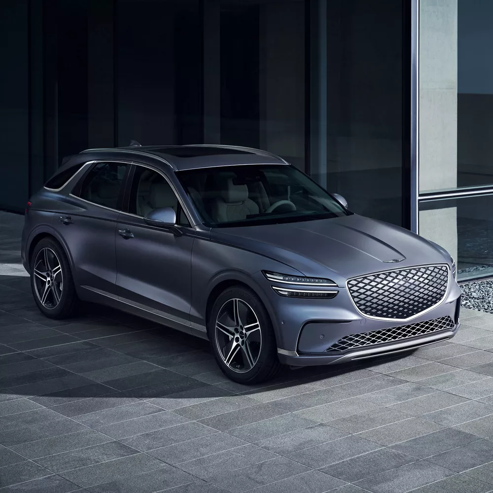 3/4 front passenger side of Genesis Electrified GV70 in Ceres Blue parked outside modern house