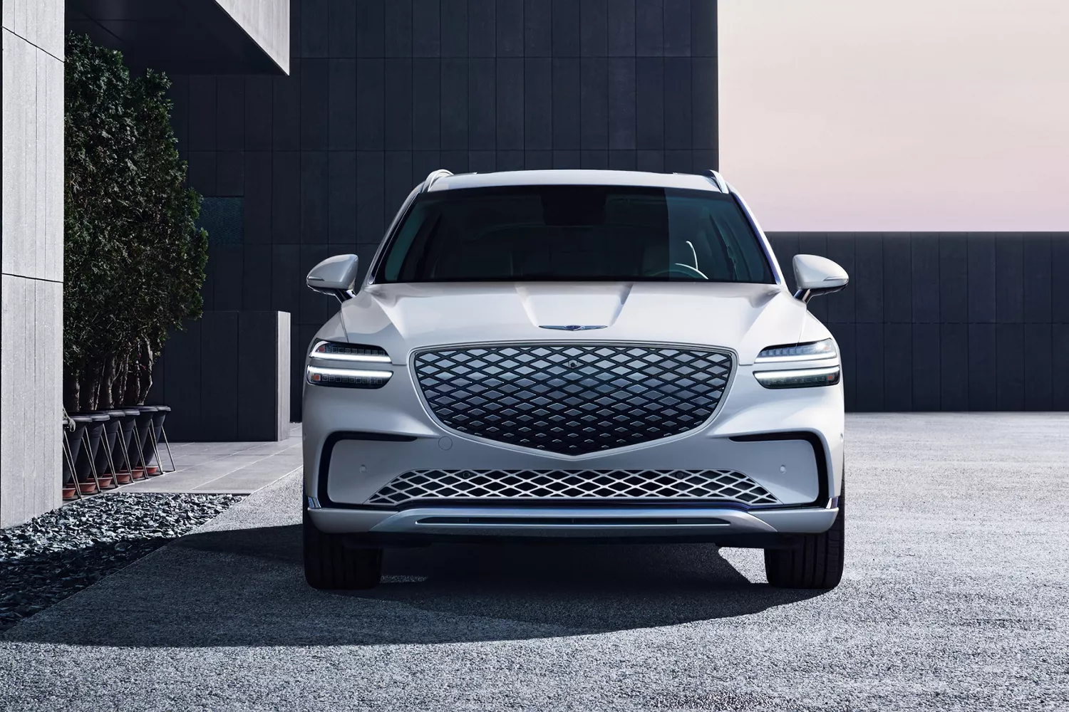Front view of Genesis Electrified GV70 in Uyuni White parked in front of a modern house