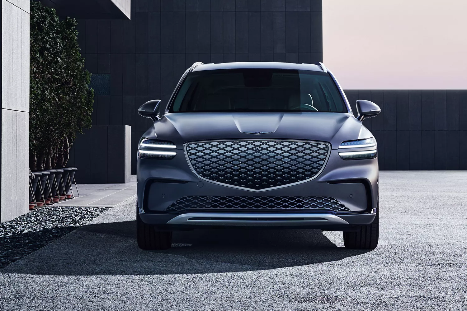 Front view of Genesis Electrified GV70 in Ceres Blue parked in front of a modern house