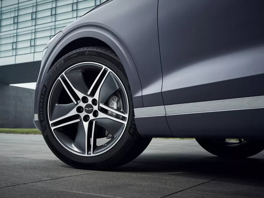 Ground level closeup of 20" dark matte gray diamond cutting wheels on Genesis Electrified GV70