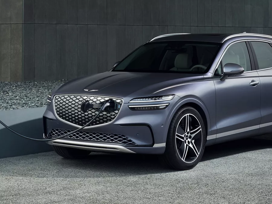 Front driver side view of Genesis Electrified GV70 connected to rapid charger through the grill