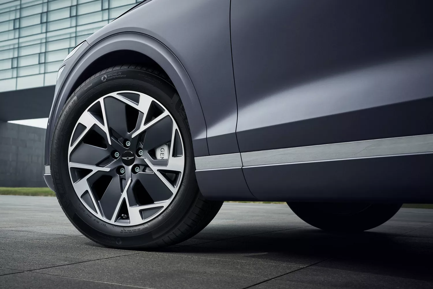 Ground level closeup of 19" dark matte gray diamond cutting wheels on Genesis Electrified GV70