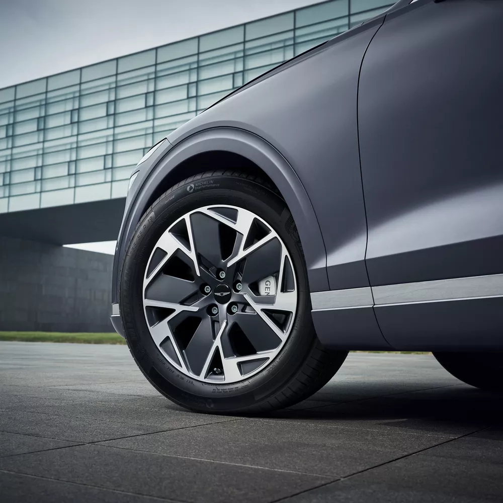 Ground level closeup of 19" dark matte gray diamond cutting wheels on Genesis Electrified GV70