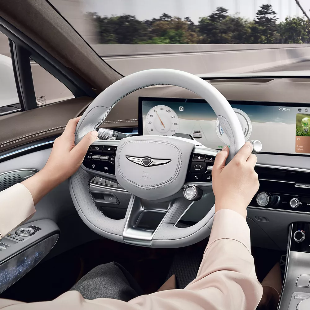 Interior close up from driver POV of hands on steering wheel inside Genesis Electrified GV70