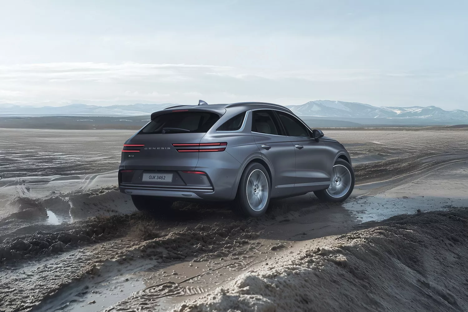 3/4 rear passenger side view of gray Genesis Electrified GV70 driving through muddy road