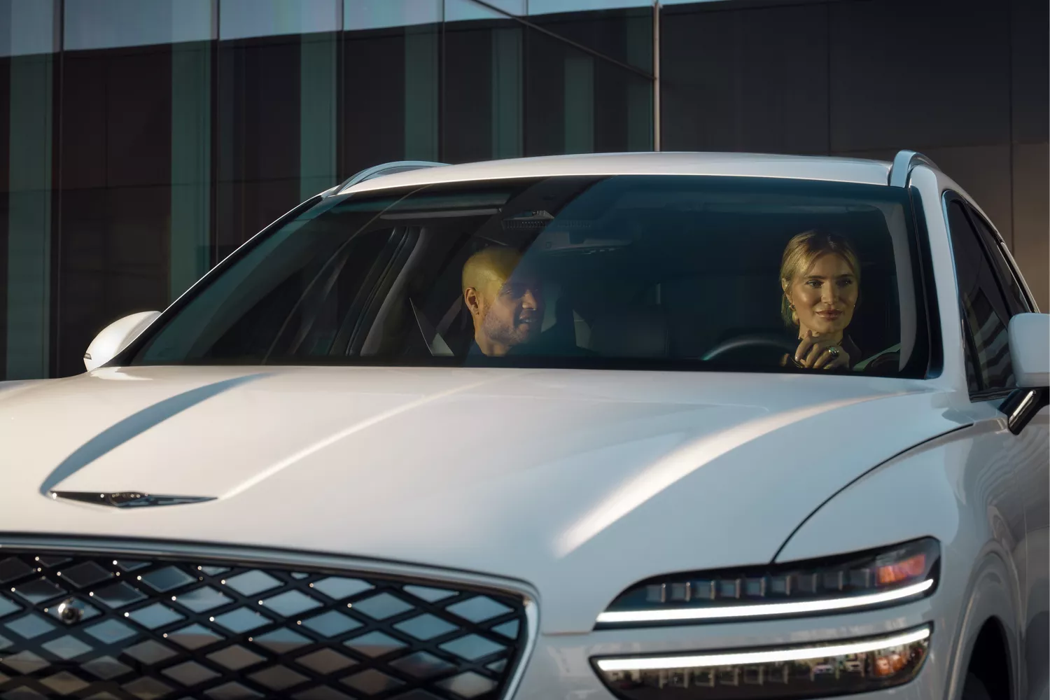 Front view of two people in front seats of Genesis Electrified GV70 in Uyuni White