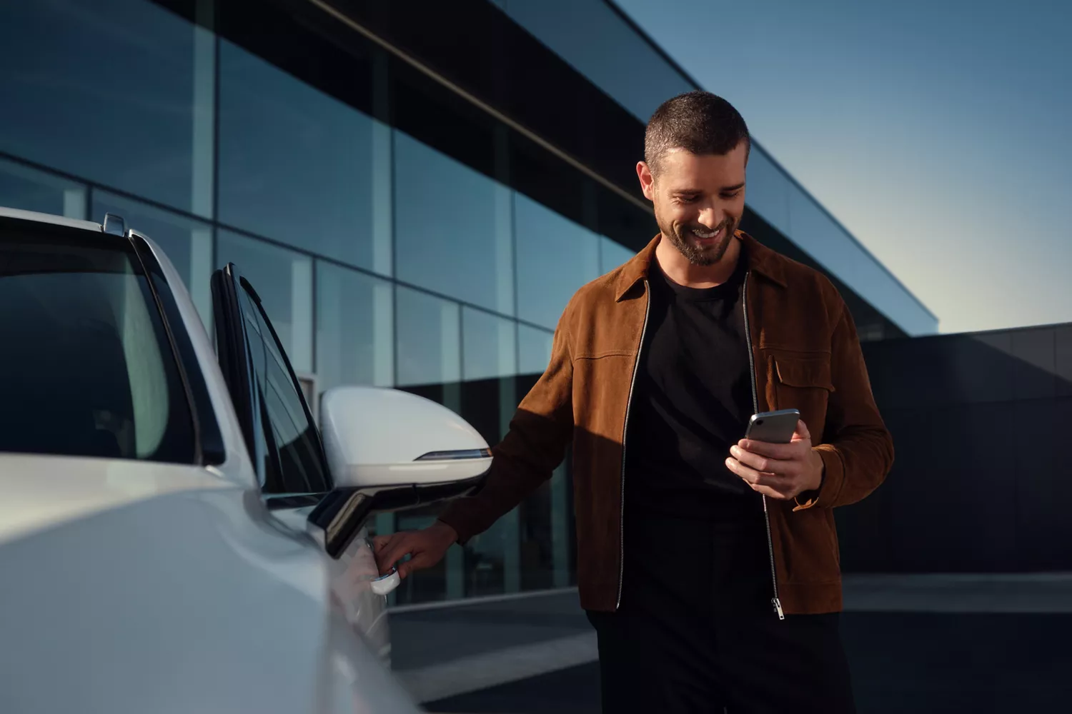 Owner opening white Genesis Electrified GV70 driver side door, unlocking with smartphone using connected services