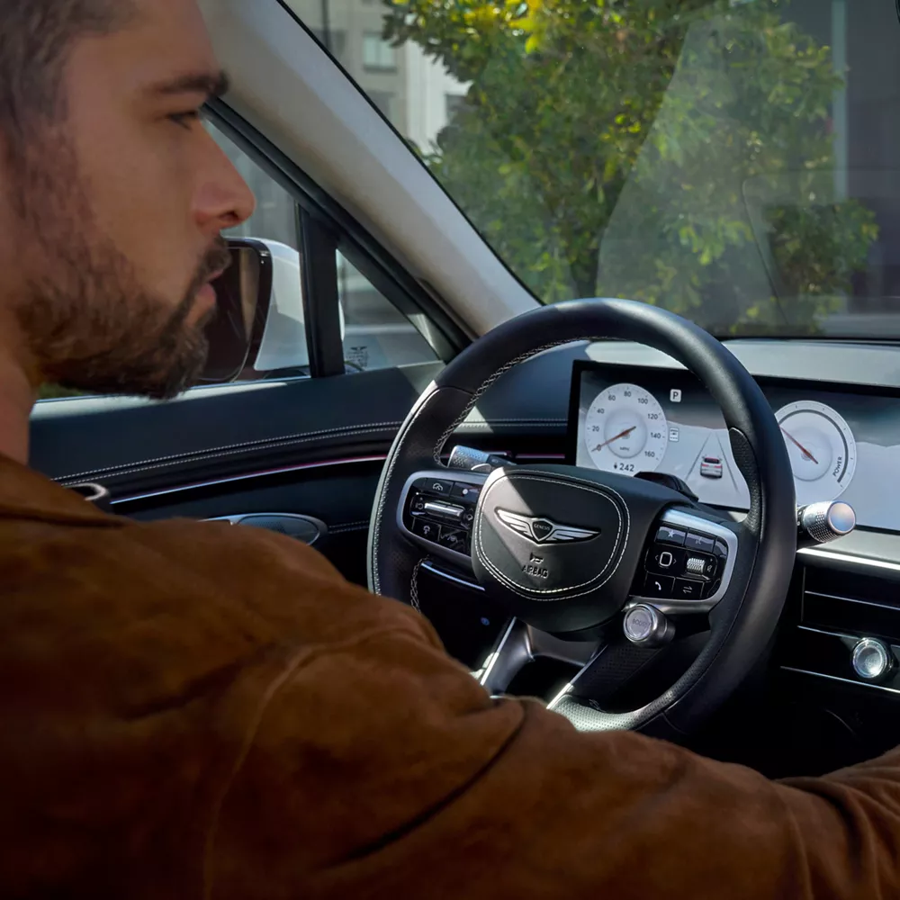 Interior close-up of driver interacting with infotainment touchscreen in Genesis Electrified GV70