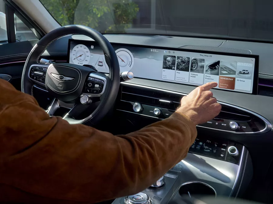 Interior close-up of driver interacting with infotainment touchscreen in Genesis Electrified GV70