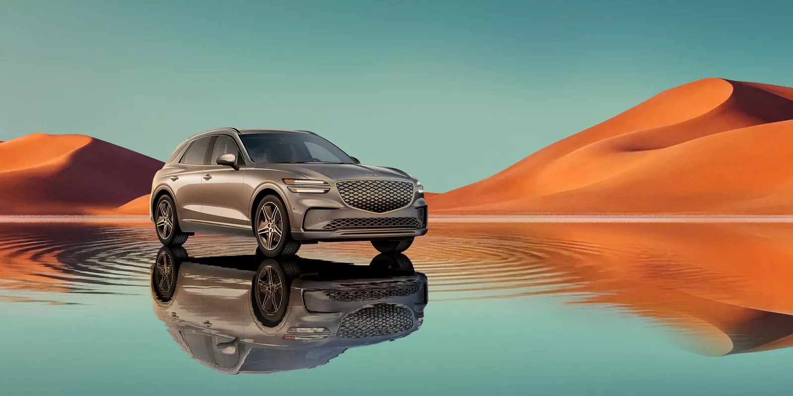 Front passenger view of Savile Silver Electrified Genesis GV70, blue lake and orange mountain behind
