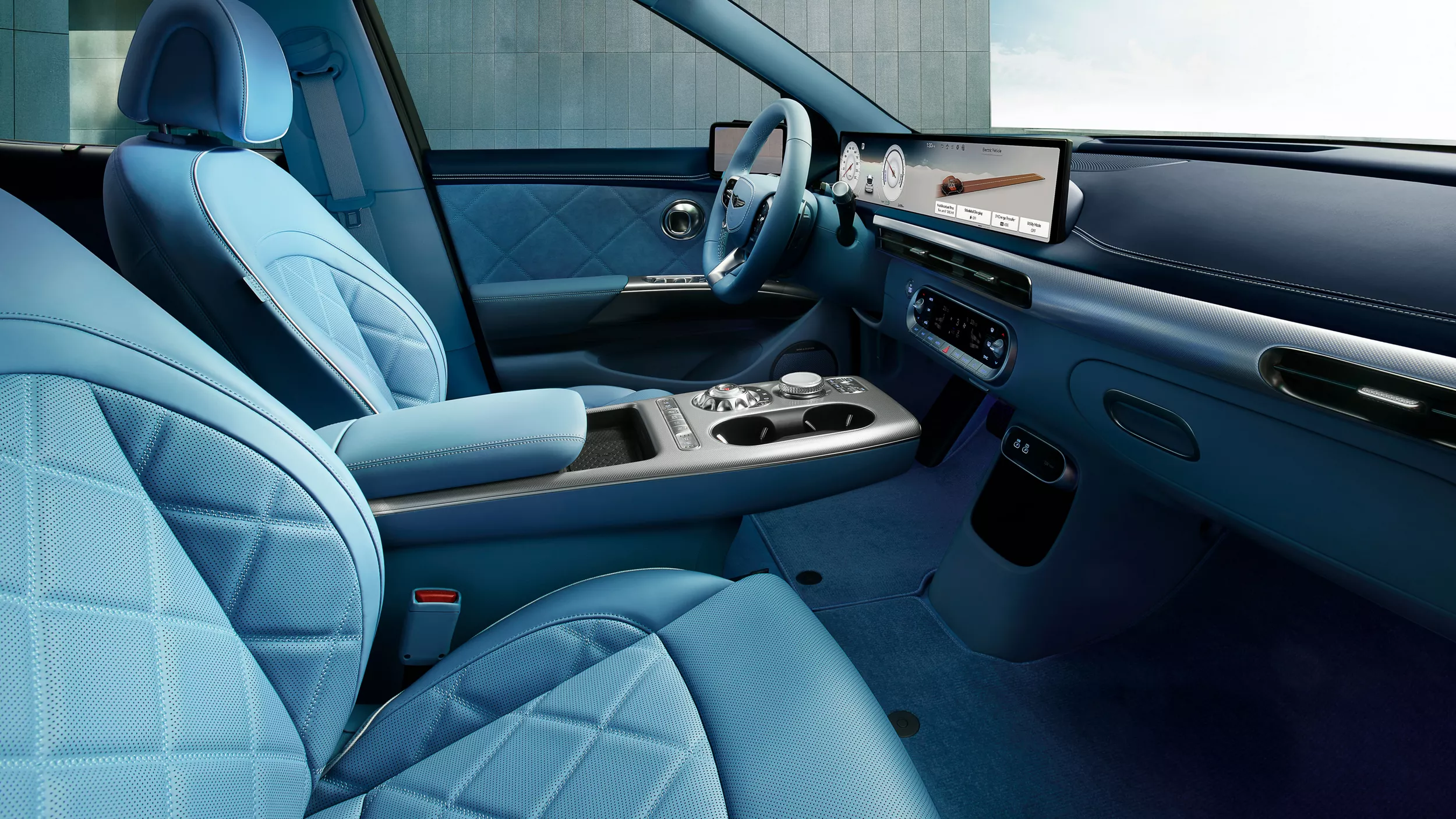 Interior passenger side cabin view of 2026 Genesis GV60 with blue quilted nappa leather seats