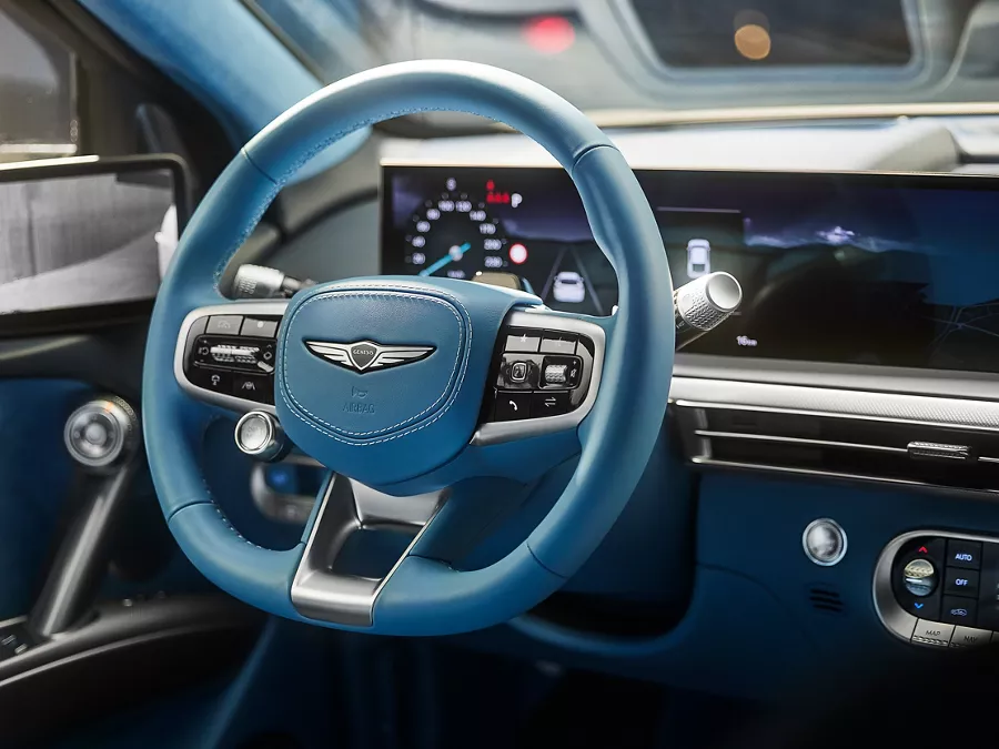 Interior shot of 2026 Genesis GV60 with blue steering wheel and touchscreen infotainment system