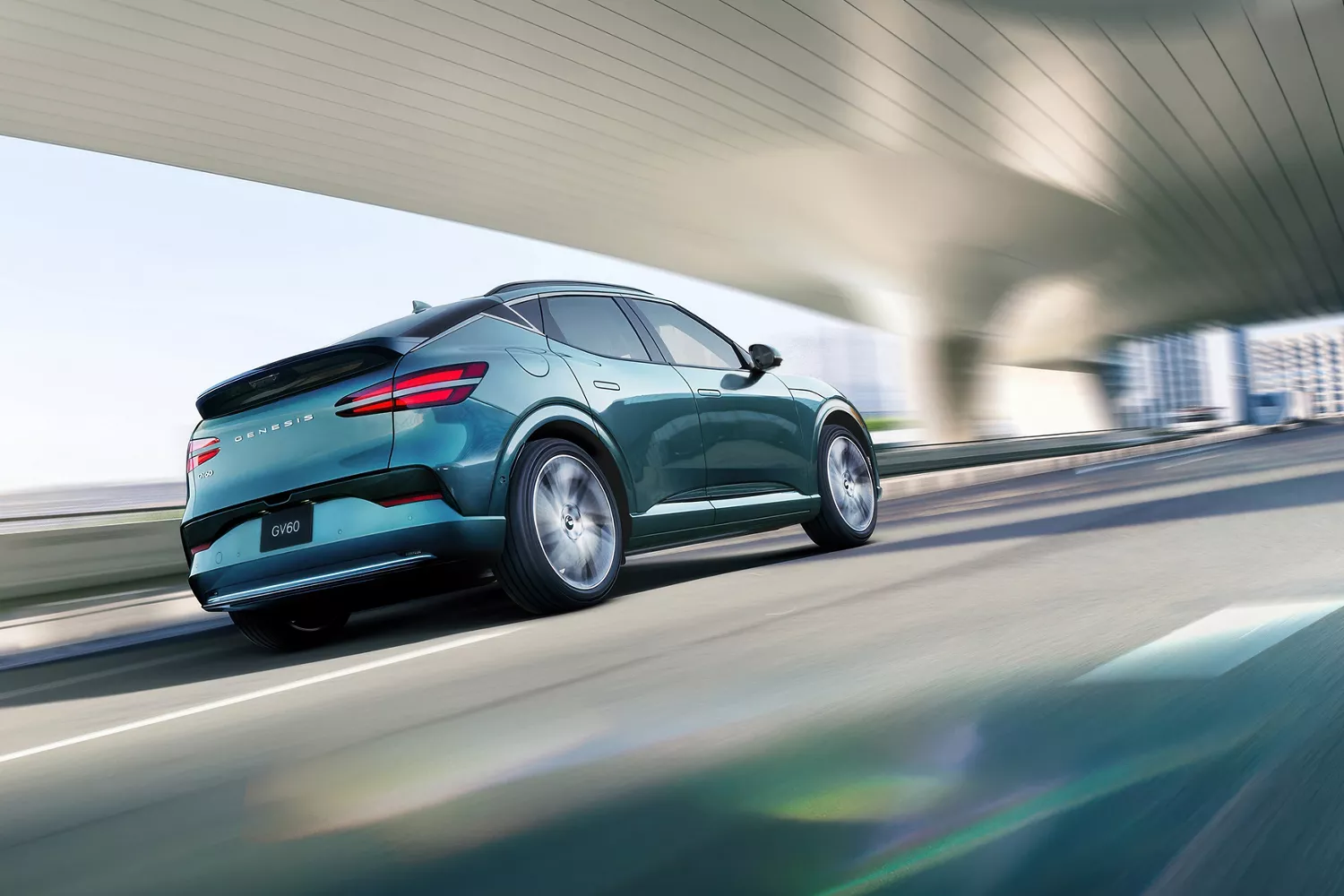 3/4 rear passenger side view of 2026 Genesis GV60 in Tromso Green driving under modern bridge