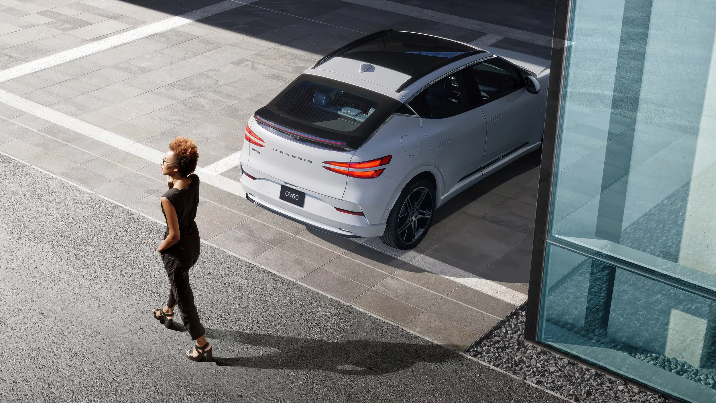 Overhead view of 2026 Genesis vehicle in Prestige Black trim, left half of the vehicle illuminated