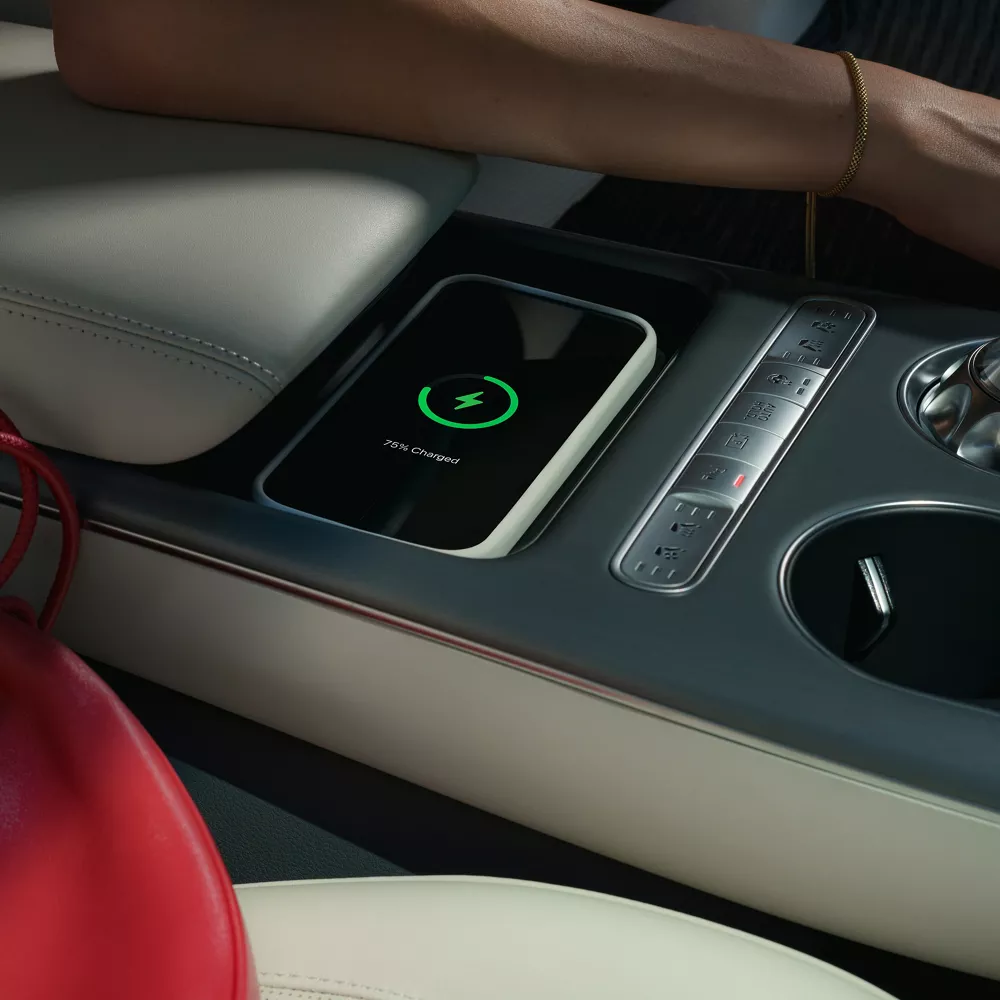 Interior close up of phone nested in wireless charging bay of center console, inside Genesis GV60