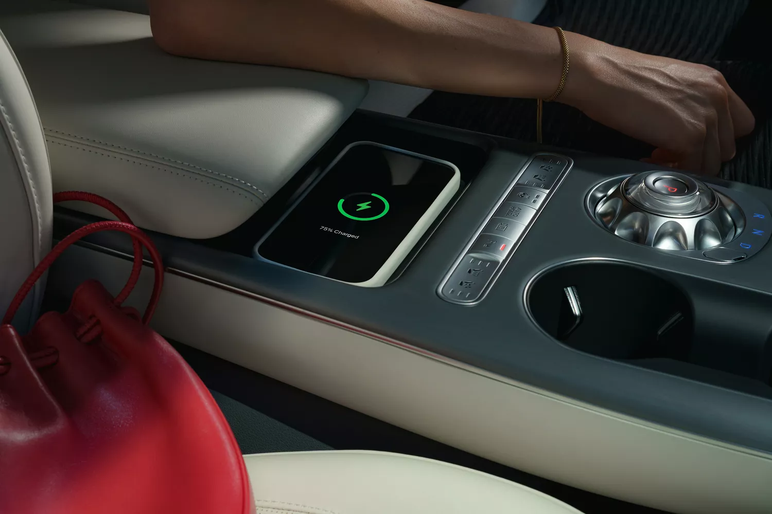 Interior close up of phone nested in wireless charging bay of center console, inside Genesis GV60