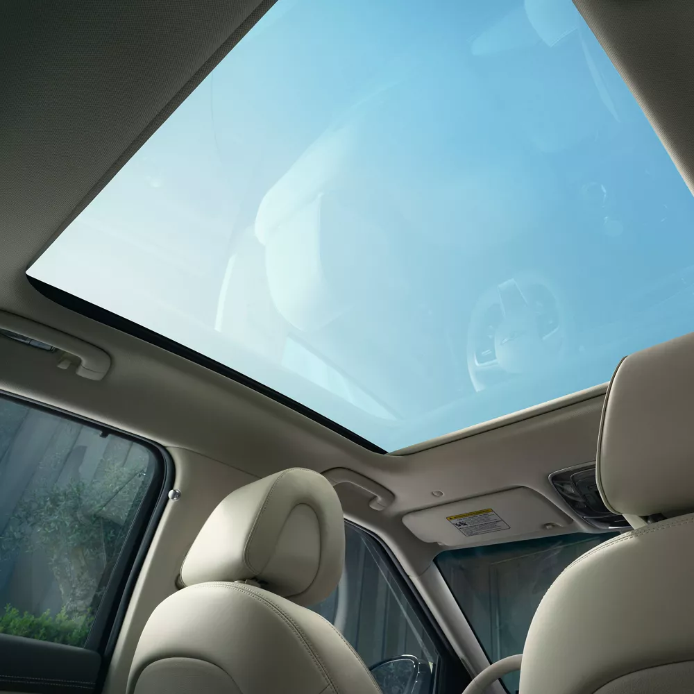 Interior view from rear passenger seat of a blue sky through the open sunroof, inside Genesis GV60