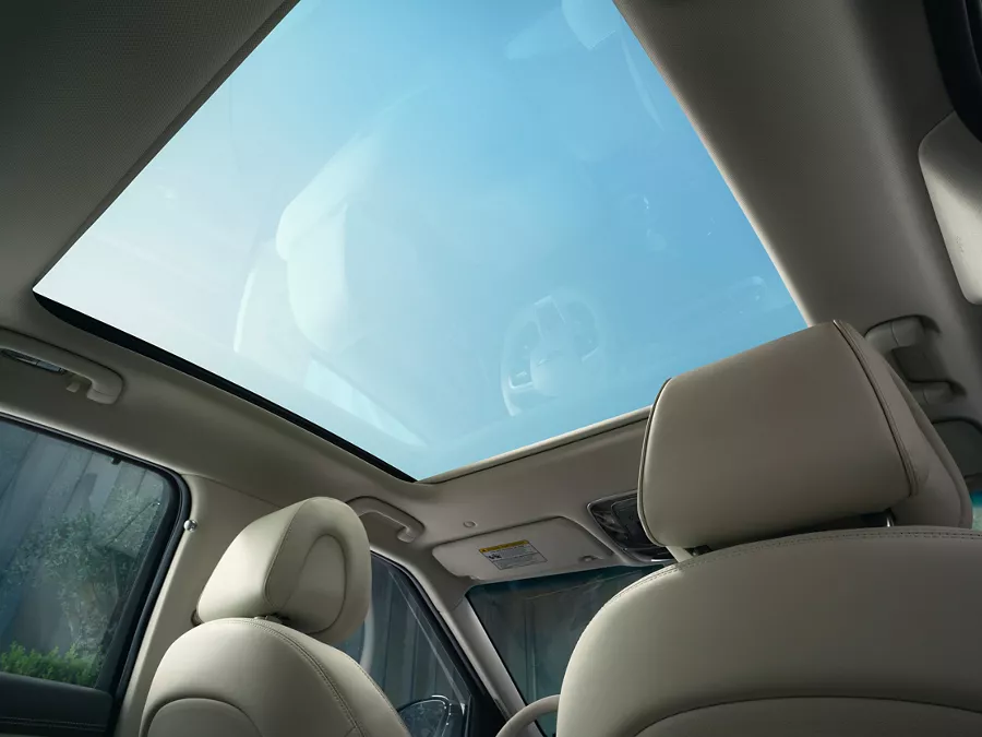 Interior view from rear passenger seat of a blue sky through the open sunroof, inside Genesis GV60