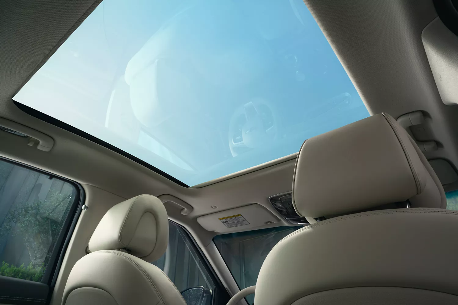 Interior view from rear passenger seat of a blue sky through the open sunroof, inside Genesis GV60